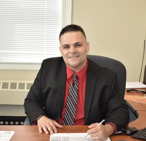 Picture of a man in a suit smiling at his desk