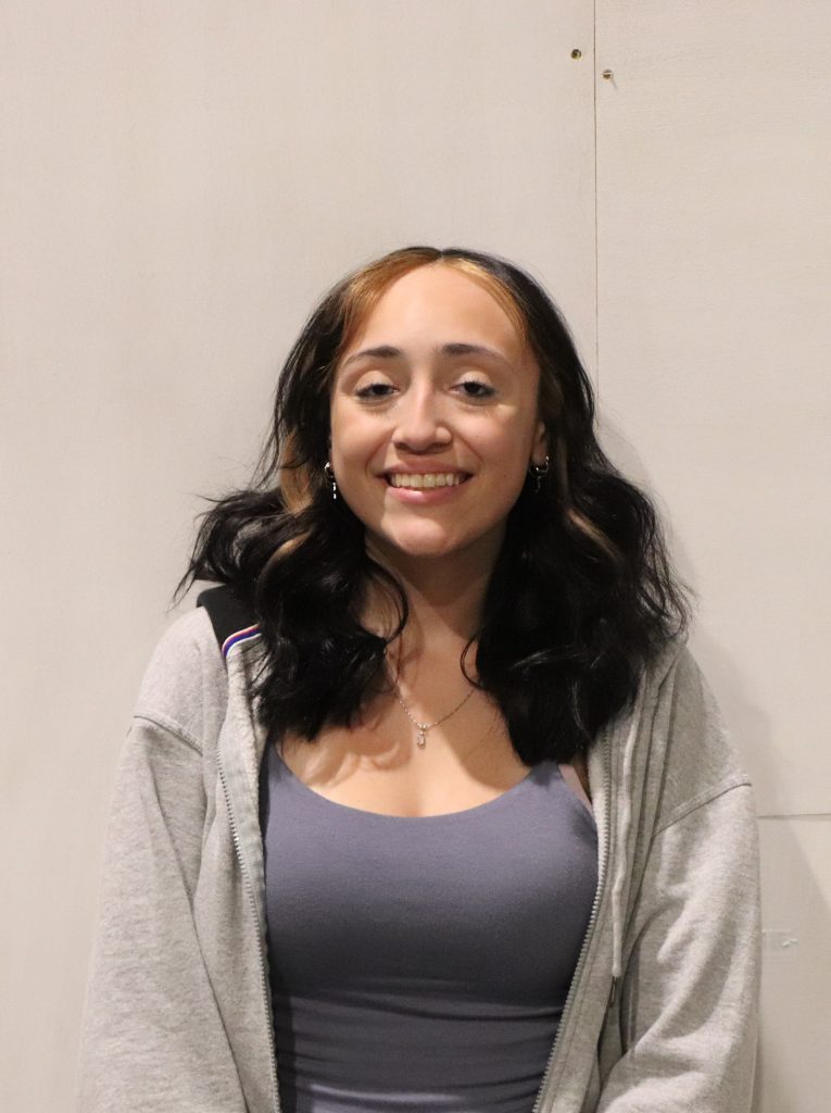 A teenager with blonde highlights framing her face smiles in front of a white backdrop.