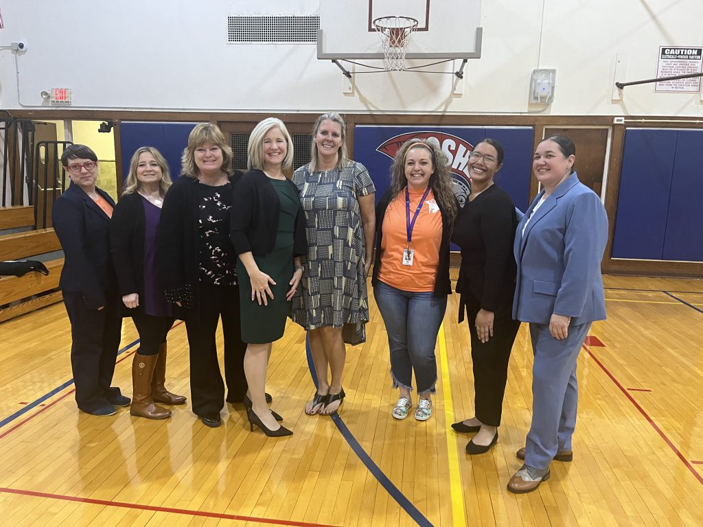 School administrators stand together in a gymnasium.