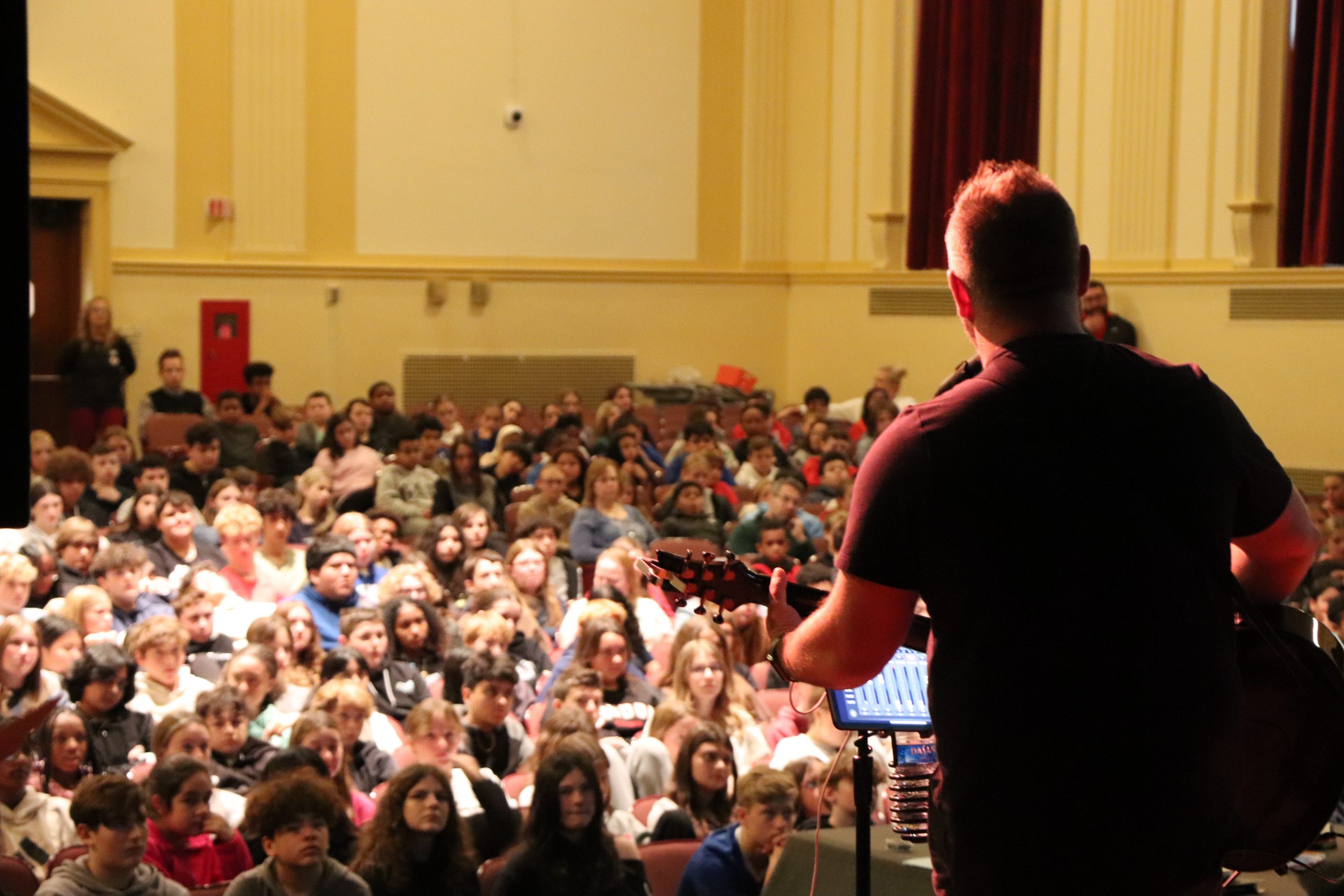 Musician Jared Campbell sings and plays guitar in the C.J. Hooker Middle School auditorium in front of the entire middle school.