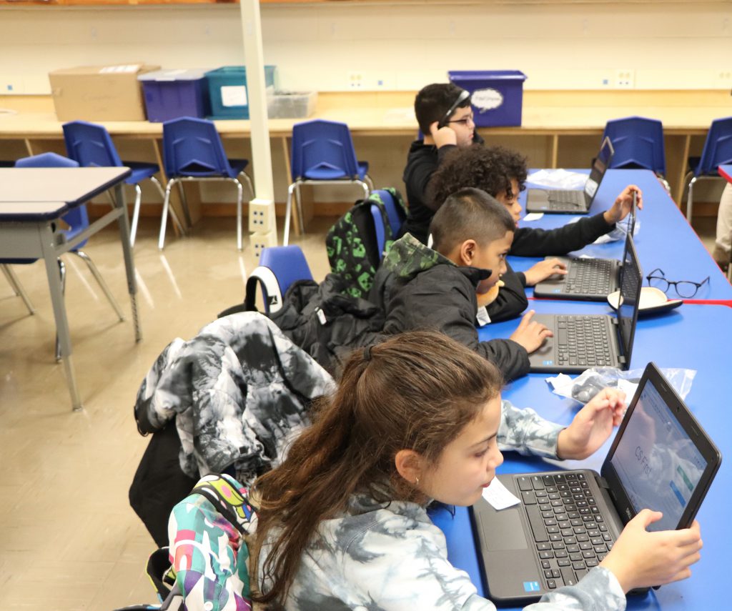 Elementary school students wear headphones and work on Chromebooks during the last session of the Coding Club at Goshen Intermediate School.