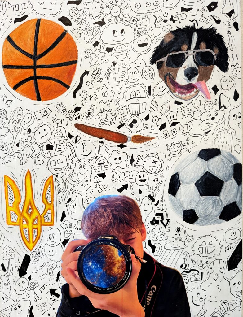 An image of black and white cartoon doodle background with a colorful orange basketball, dog with sunglasses, paintbrush, yellow symbol and soccerball. A boy with a camera that has the galaxy in the lens is in the front center. 