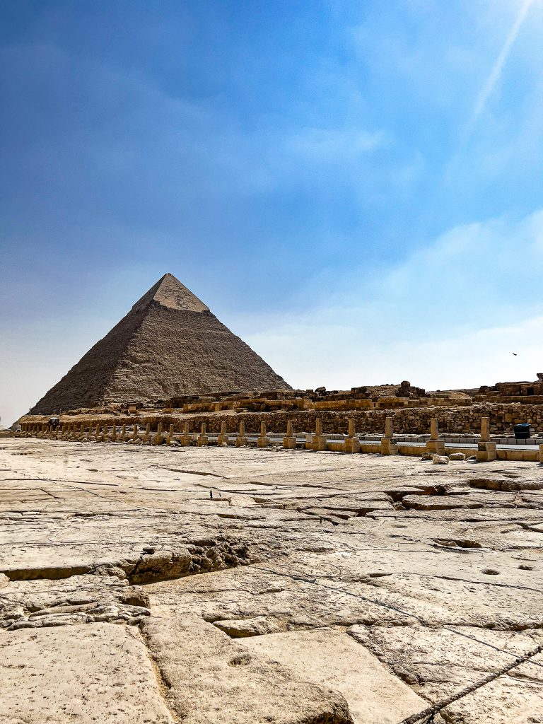 Photograph of the pyramids of Giza with a bright blue sky in the background.