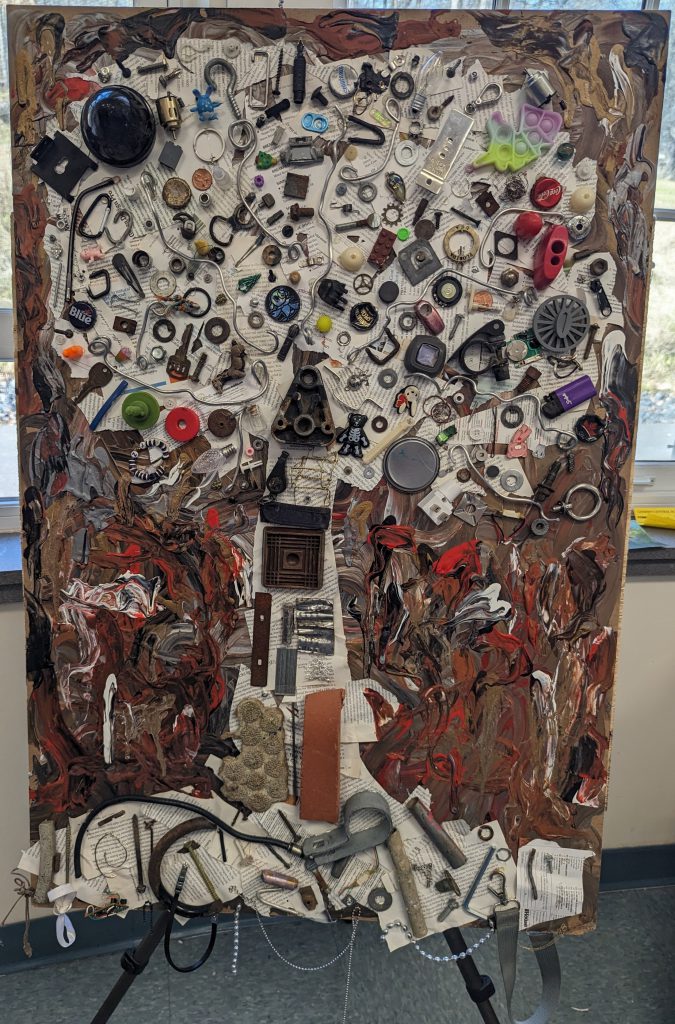 A mixed media art piece made of metal and objects in the shape of a tree.