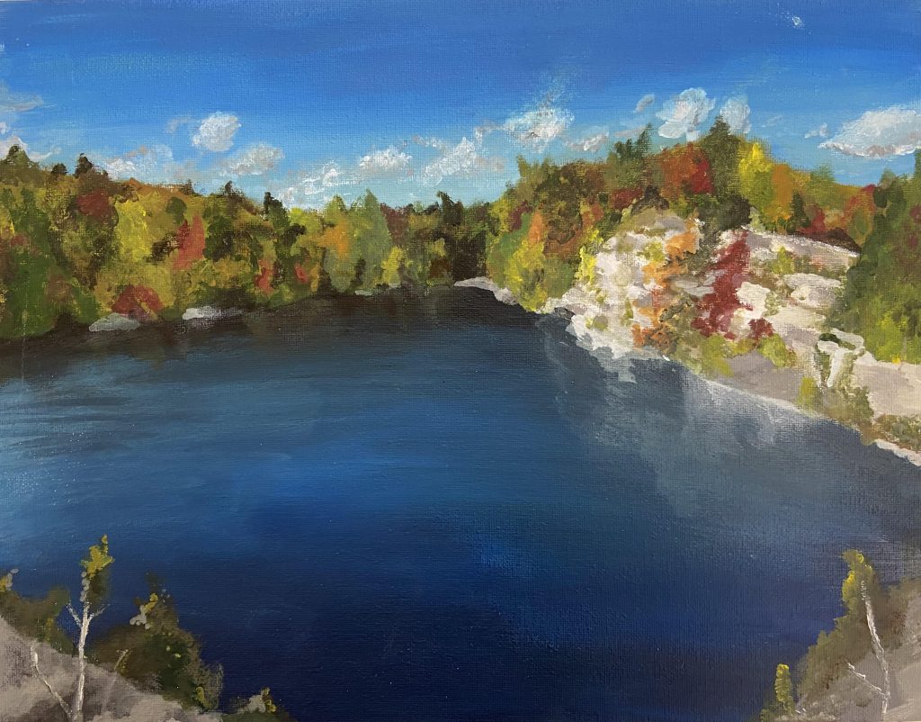 Painting of a big blue lake surrounded by fall trees with colorful leaves and a bright blue sky with white clouds.