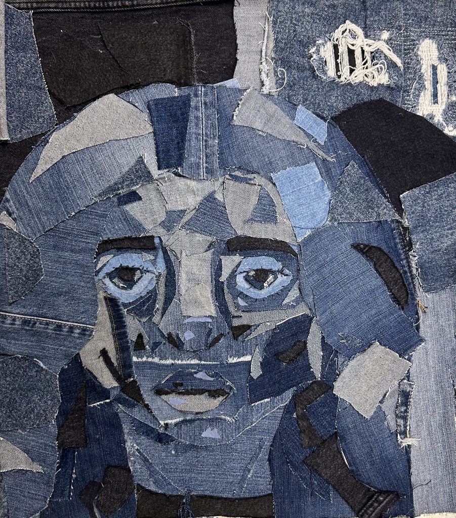 Self portrait made with cut pieces of different colored denim in the shape of a face. 