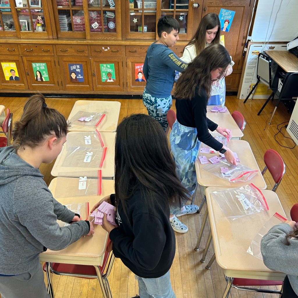 Middle school students put Valentine's Day grams into Zip-loc bags.