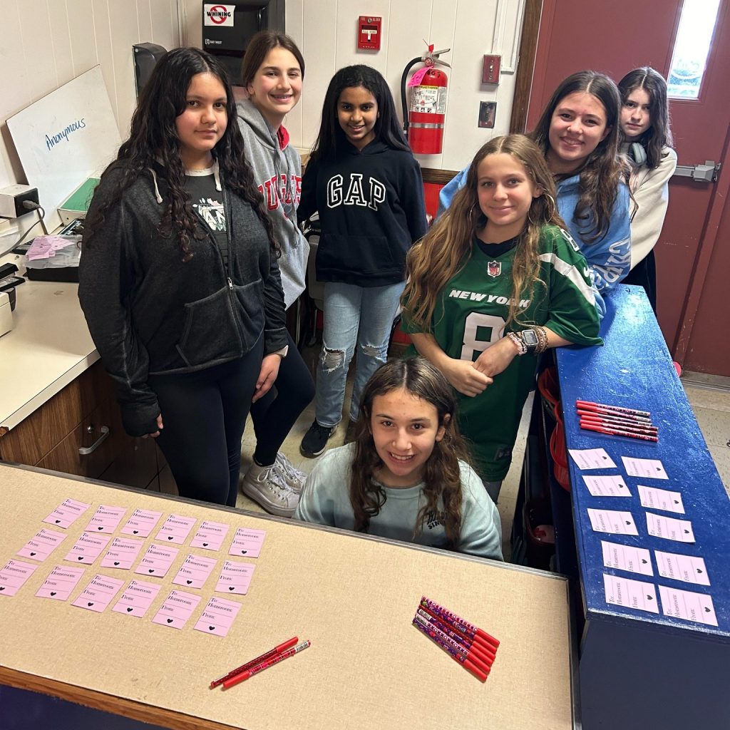 Middle school students smile next to their Valentine's Day grams. 