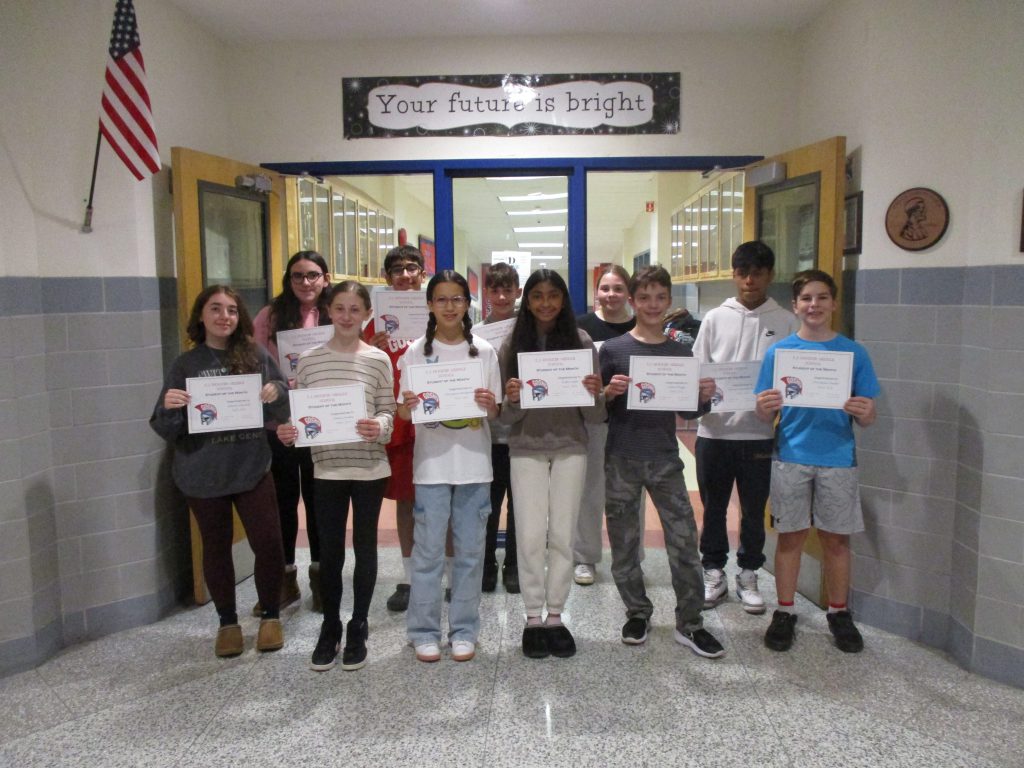 A group of middle school students stand together smiling with certificates in a school hallway in front of a sign that says "Your future is bright."
