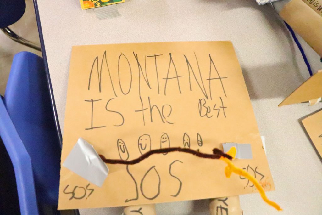 A sign made of cardboard with tape holding pipe cleaners to the sign to make a hoop. The sign reads Montana is the best