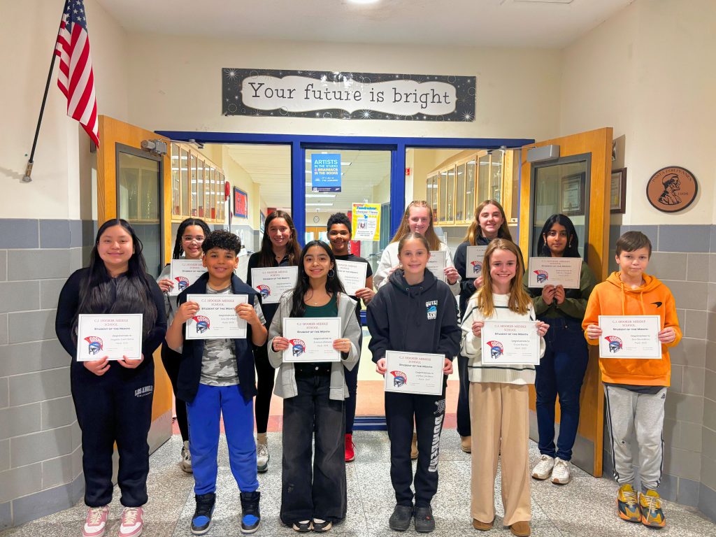 Students from CJ Hooker hold their students of the month certificates in front of a "Your Future is Bright" sign in the hallway. Each students is smiling for the photo and looking at the camera.