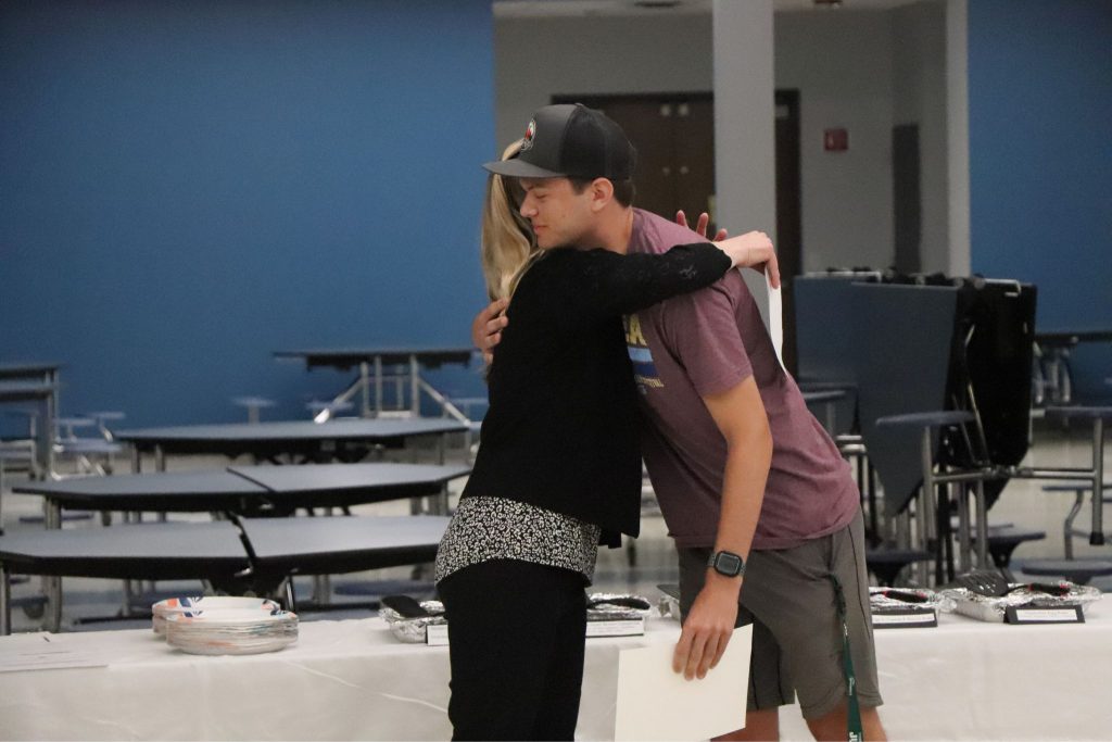 A student hugs his teacher in the cafeteria.