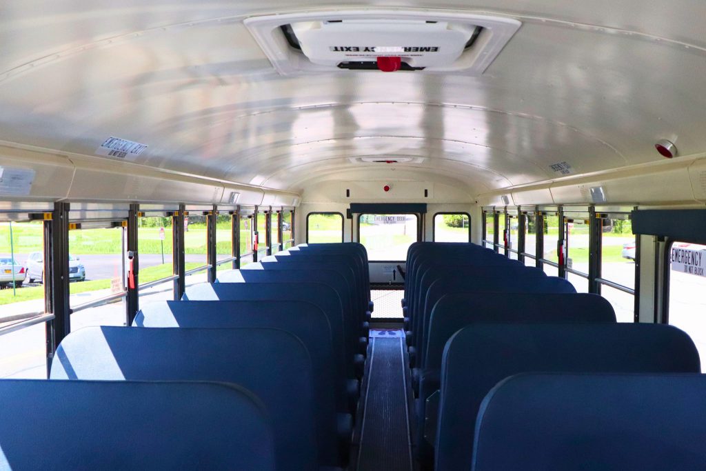 The seats in Goshen's new electric buses look like the seats in a regular school bus. The picture is taken from inside the bus looking back at the back door.
