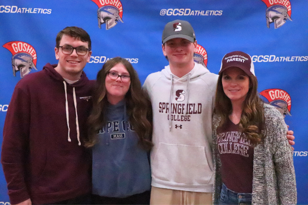Colin Butryn stands and smiles with his family. There are two people to his right and one to his left. They are wearing Springfield shirts, hats and sweaters.