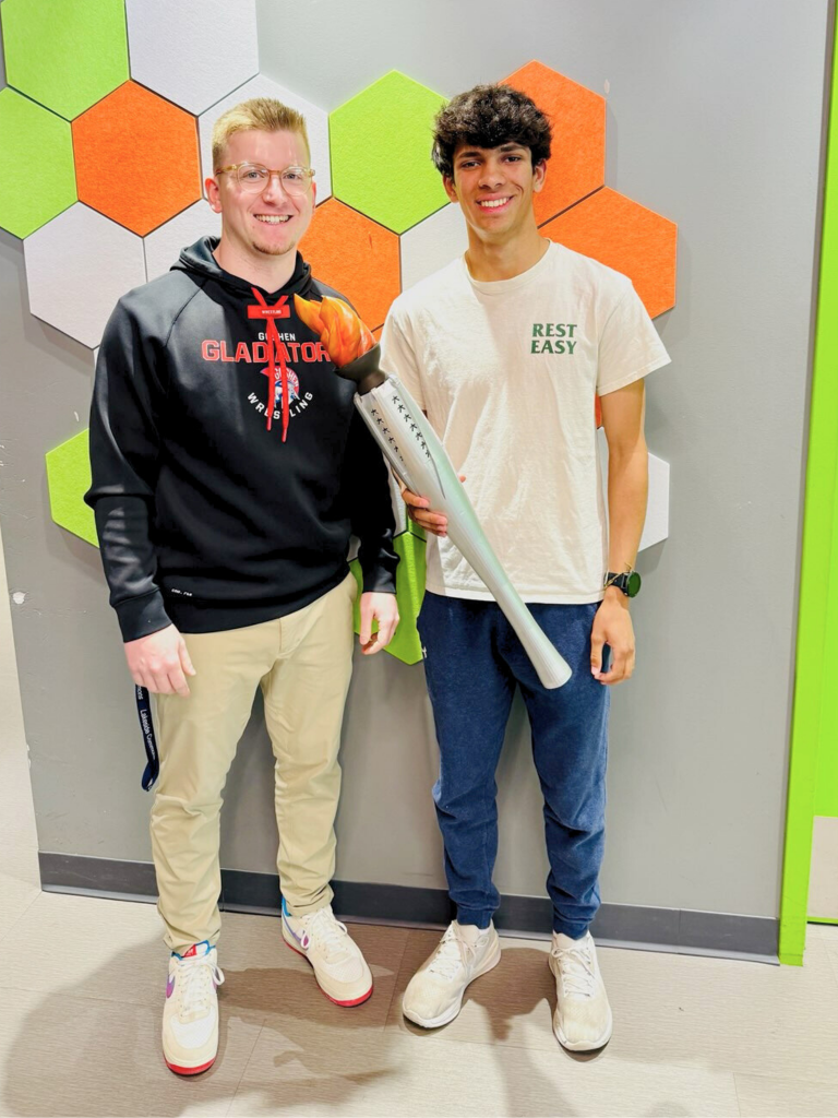 Mr. Johnson and Kiran Foster stand next to each other in Goshen High School with the 3D printed olympic torch and smile for the camera.