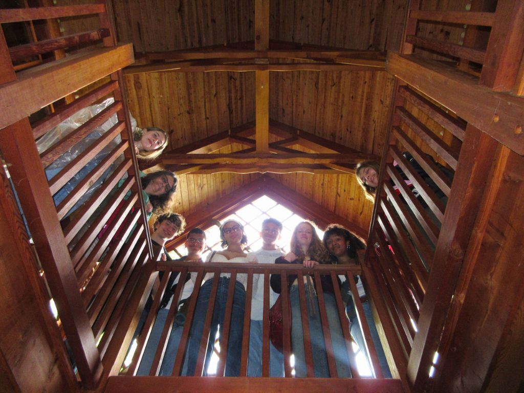 Students are on a balcony looking down at the camera from above.