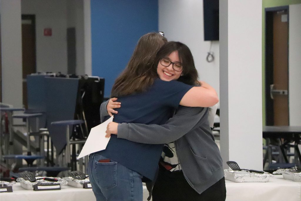 A teacher and student hug during the Goshen Greats Breakfast in the cafeteria.