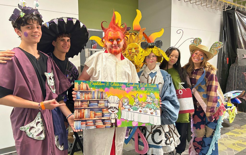 Team Seligman is posing for a photo in costume at the World Finals. Some are dressed like animals, the sun, and all are wearing hats.
