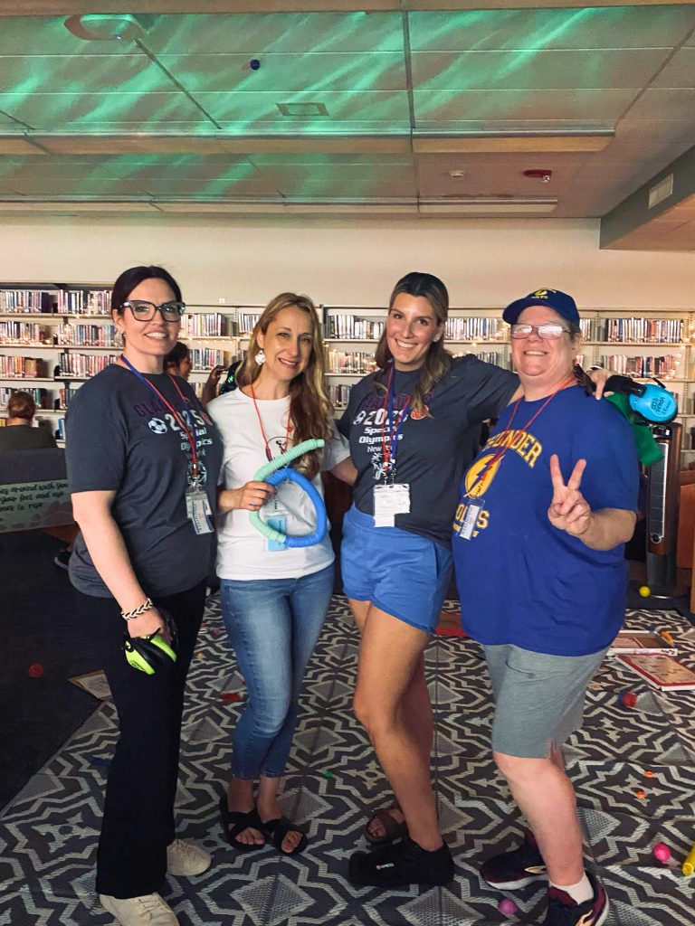 Four Goshen staff smile and look at the camera. They worked on the preparation for the Special Olympics. They are wearing Special Olympics shirts.