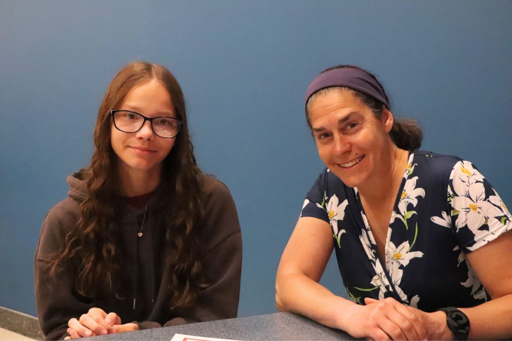 A teacher and a student smile while sitting at a lunch table during the Goshen Greats breakfast.