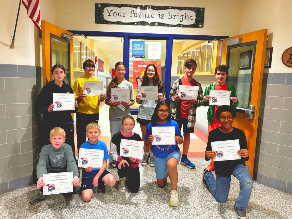 The April Students of the Month are in the hallway of C. J. Hooker Middle School and smiling for a photo. They are holding certificates and are under a sign that reads: your future is bright.