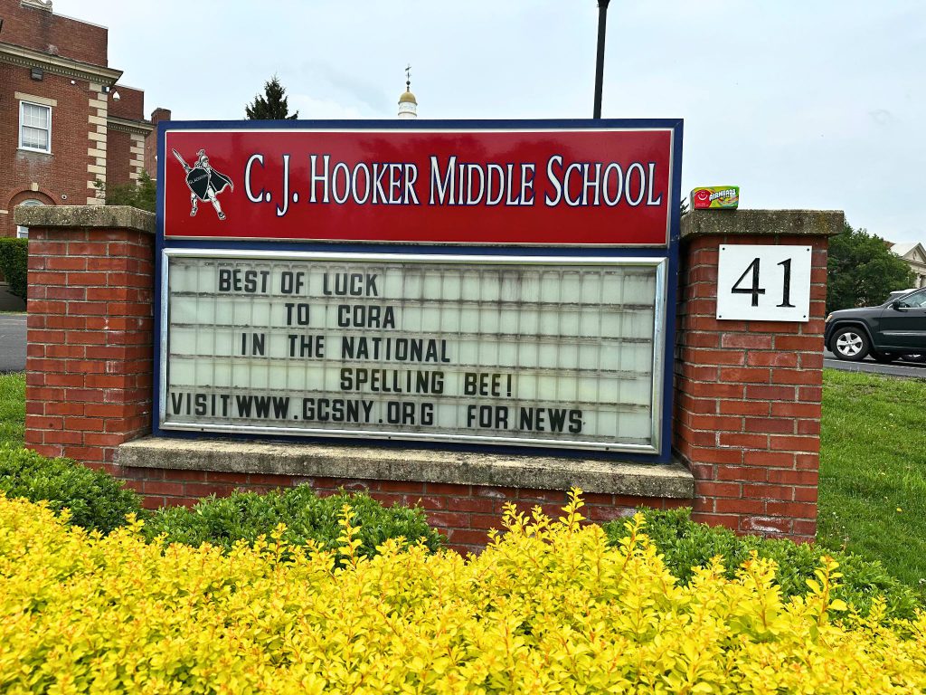 The C. J. Hooker Middle School sign in front of the school has a message that reads :Best of luck to Cora in the National Spelling Bee! Visit www.gcsny.org for news.