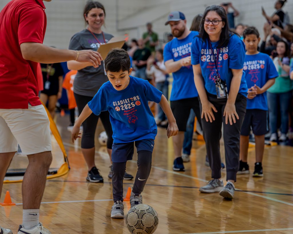 A Goshen student is approaching a soccer ball about to kick it during a competition during the Special Olympics in Goshen High School.