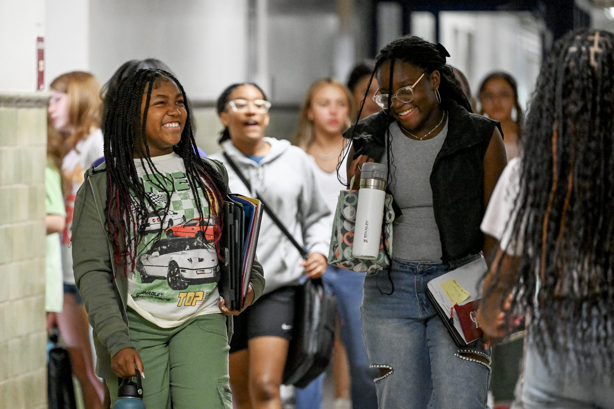 Two students walk down the hallway and smile in the middle school. 