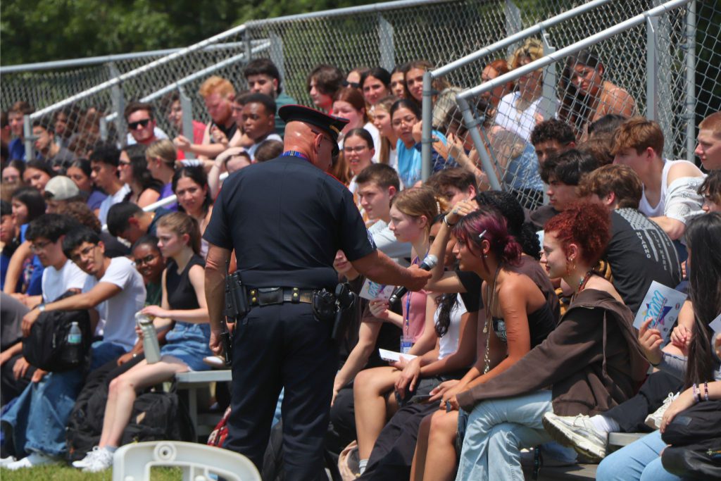 A police officer extends a microphone out to speak to a student in the crowd at the drill.