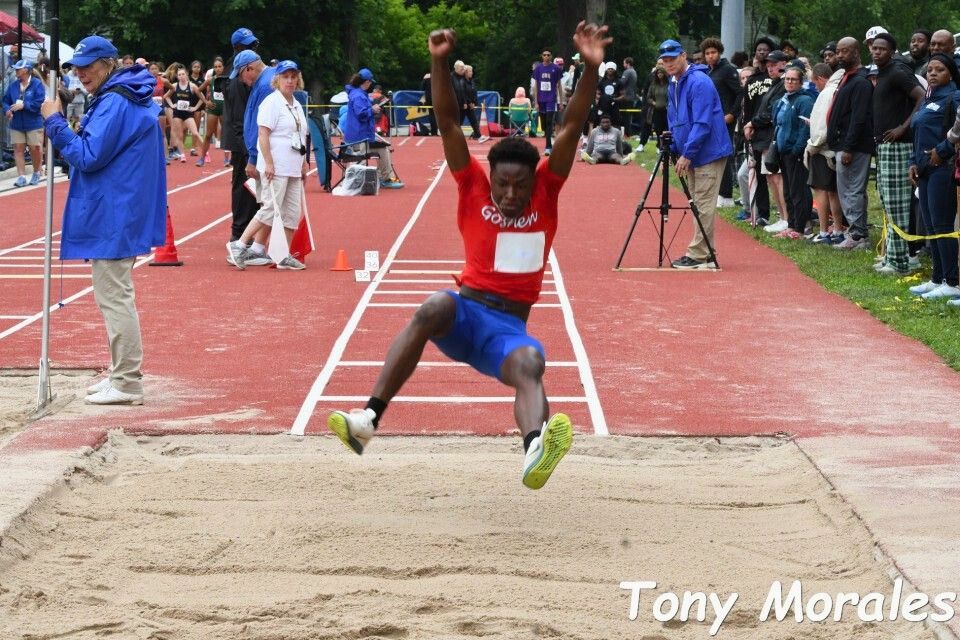 Jeangardy Louis jumps in the air on his way into the sand pit at the New York State championship meet.