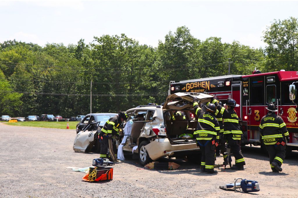 Firefighters are pulling the doors off of a car during the mock crash simulation.