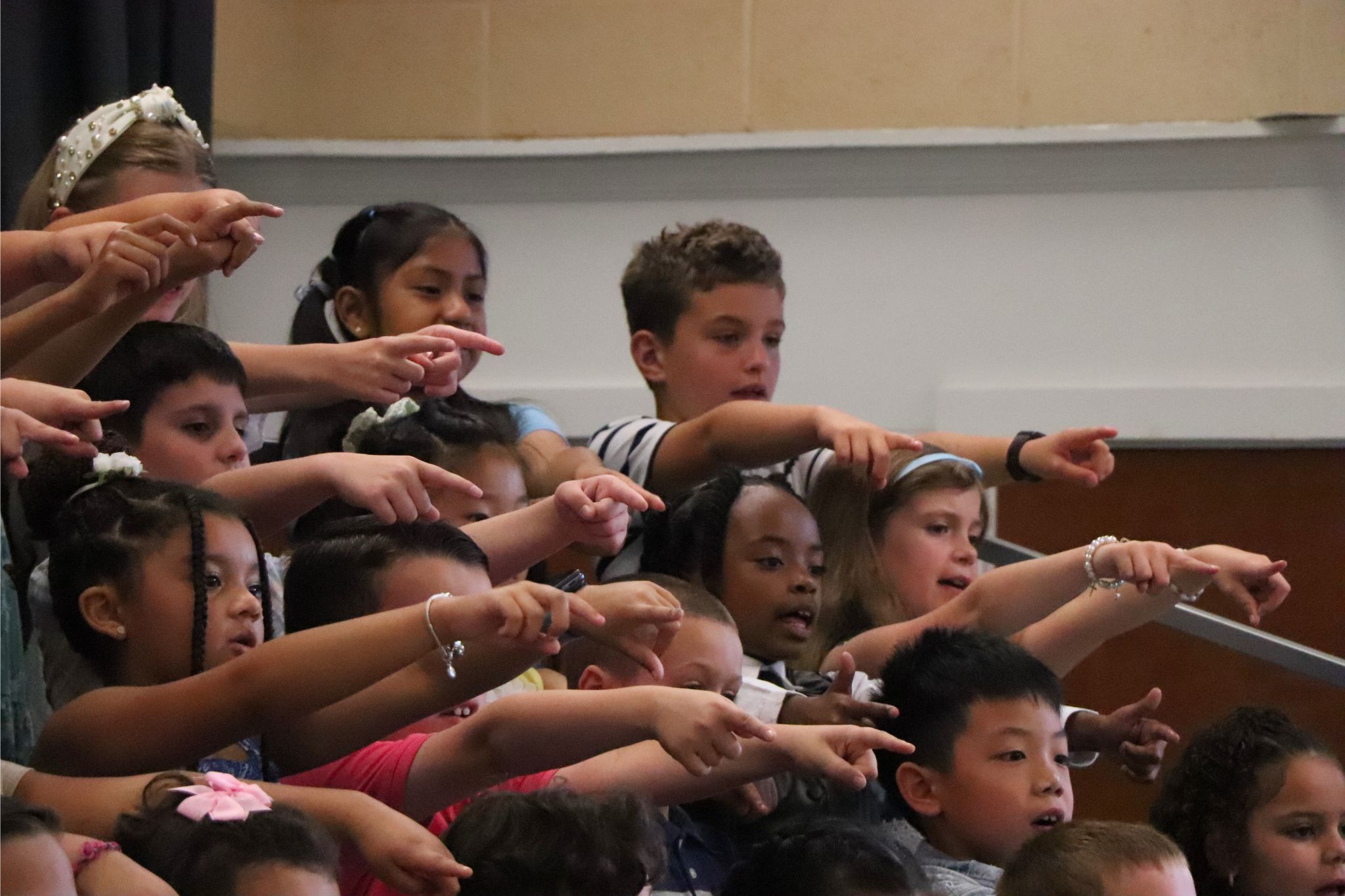Students performing on stage pointing out to the crowd. 