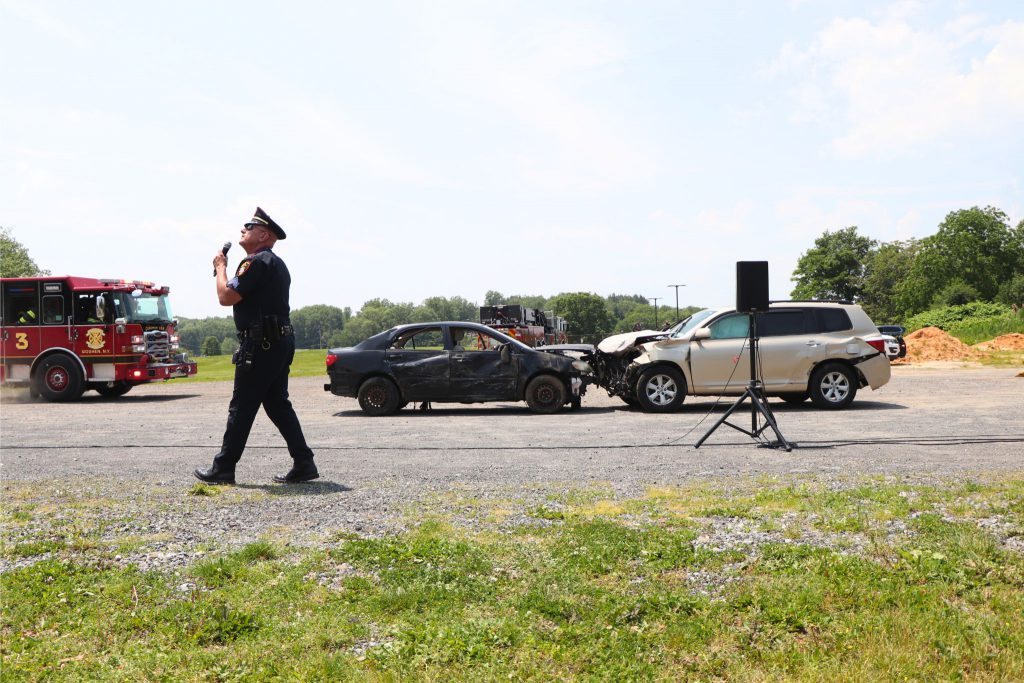 A fire truck arrives on scene as a police officer is talking with the two cars having simulated a crash at the drill outside near Goshen High School.