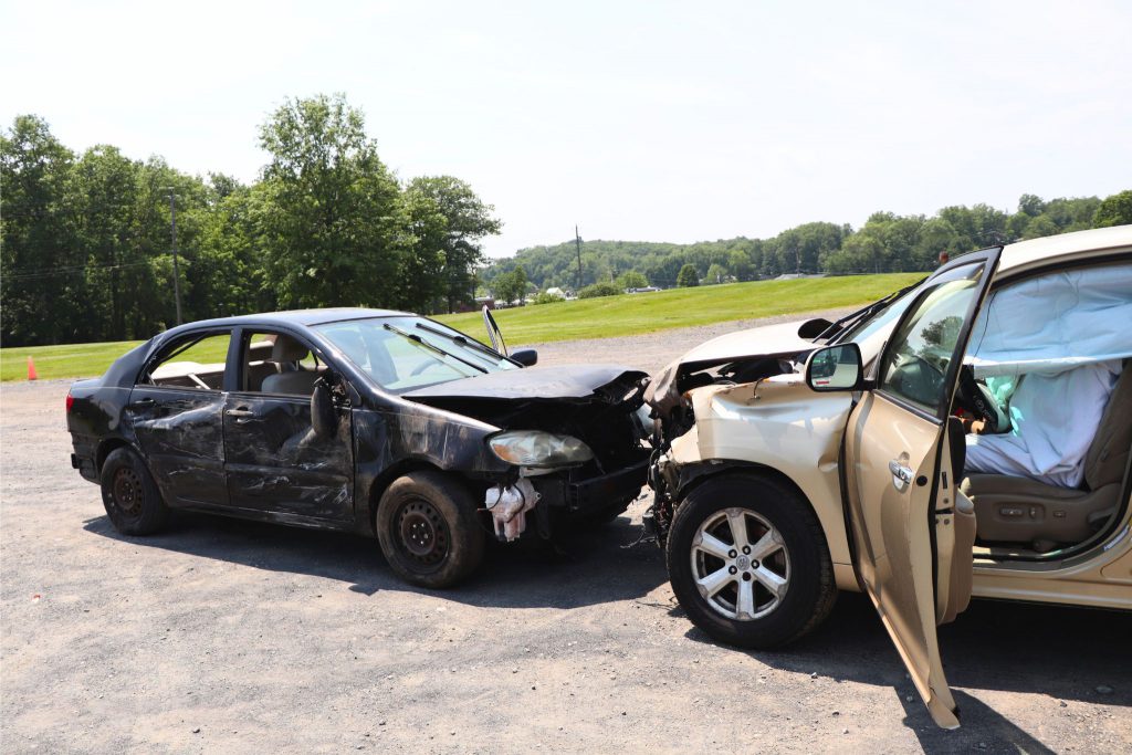 Two cars are shown to have collided together in the gravel parking lot at Goshen High School as part of the drill. The fronts of the cars are mangled from the simulated accident.