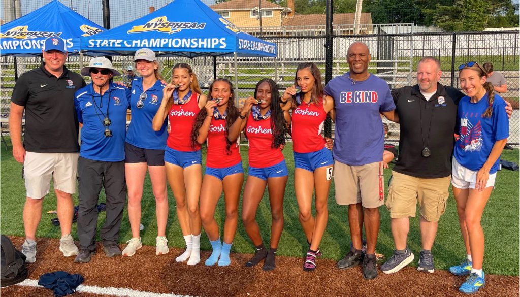 The Goshen girls four by one team, along with the coaches, smile together for a photo near the track.