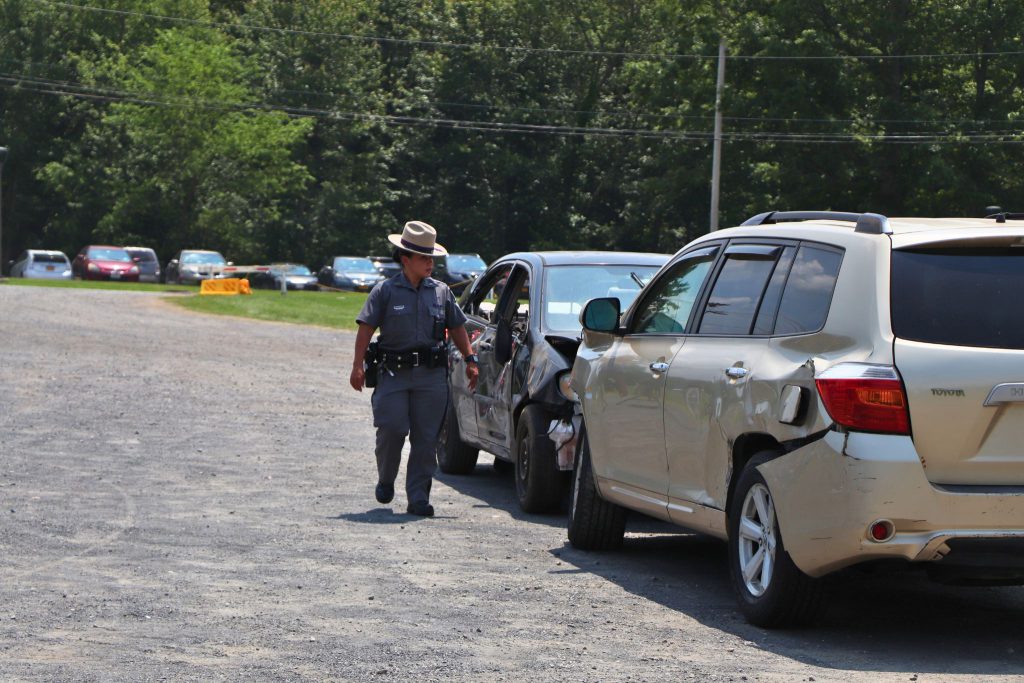 A police officer walks past two cars that have supposedly crashed together during a mock crash drill at Goshen High School.