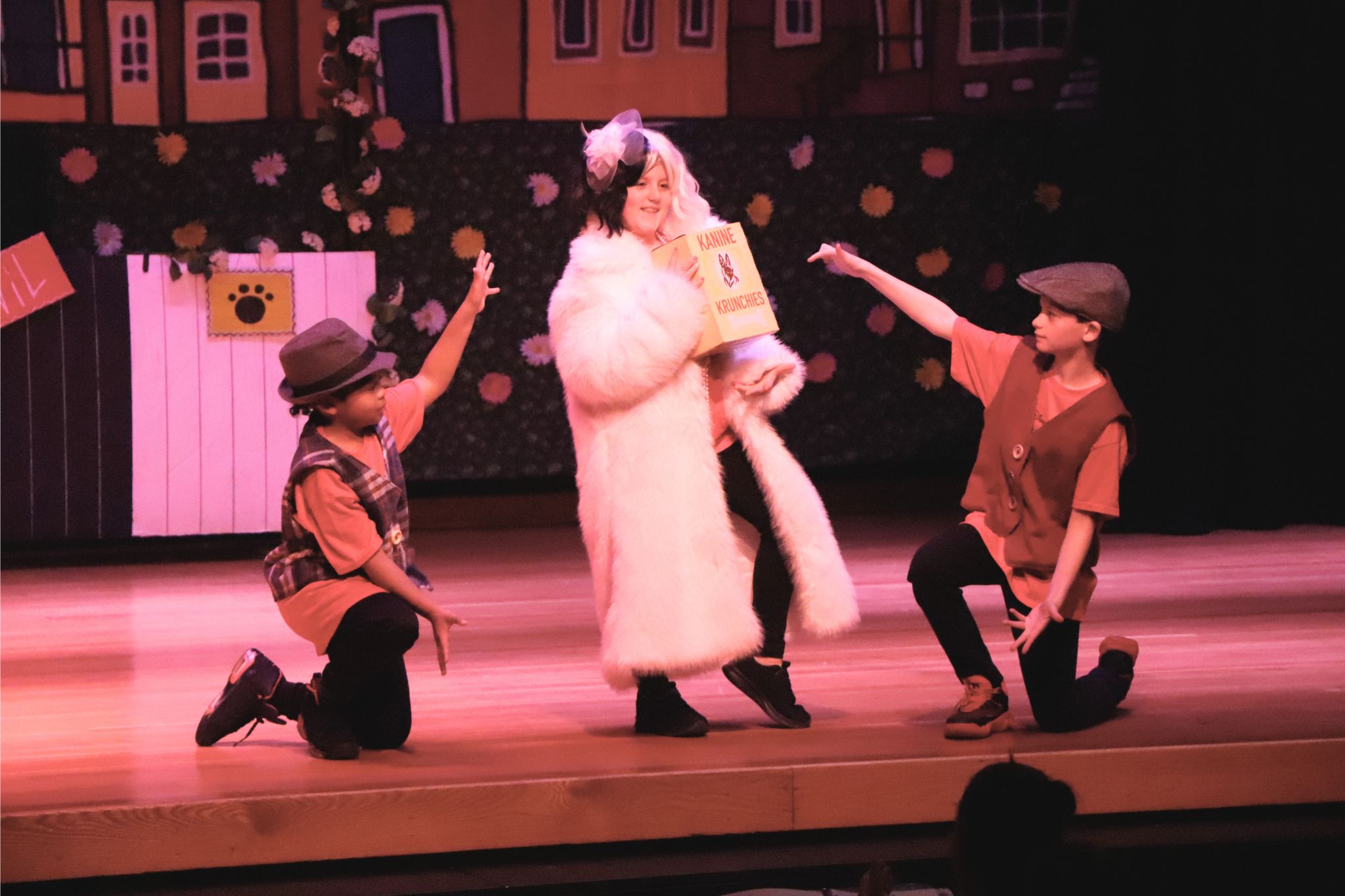 Two students point to a student in between them during the 101 Dalmations production. 