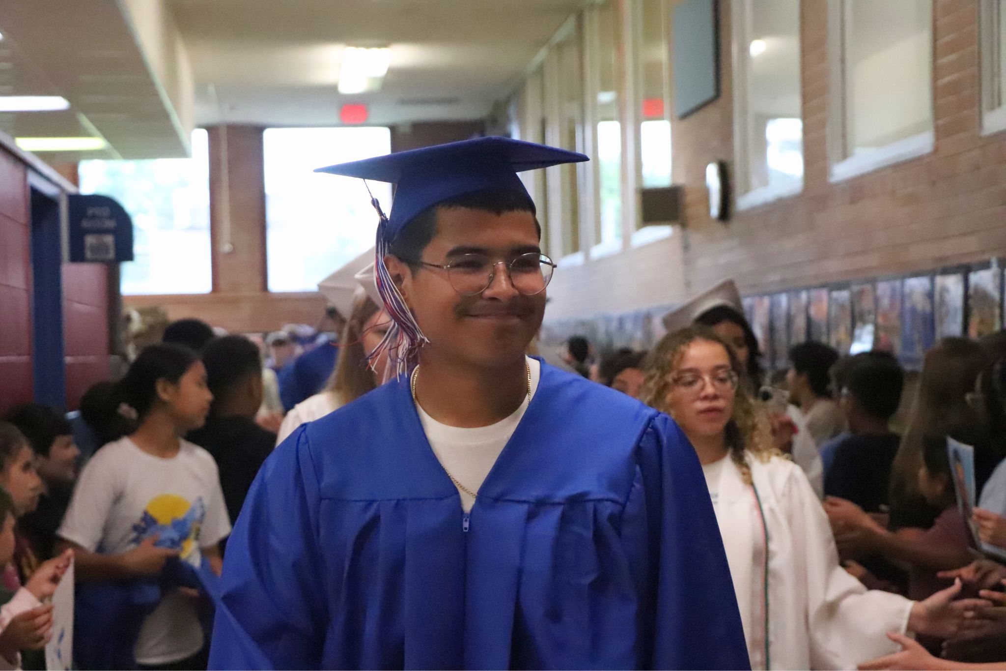 A student smiles while walking down the hall in the senior walk through. 