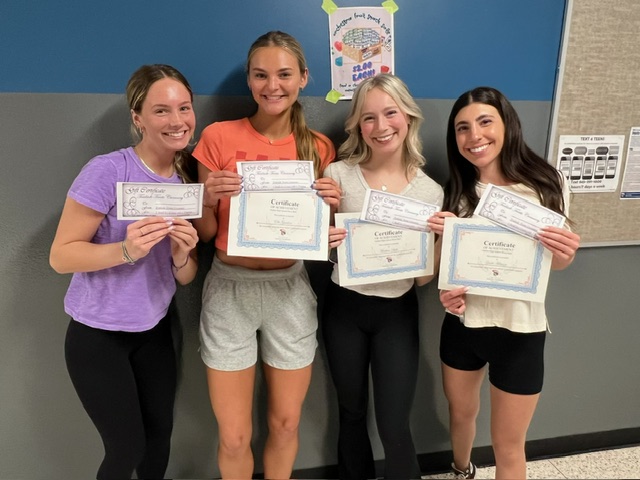 Four students smile and stand in the hallway with their gift certificates from Trailside Treats. 