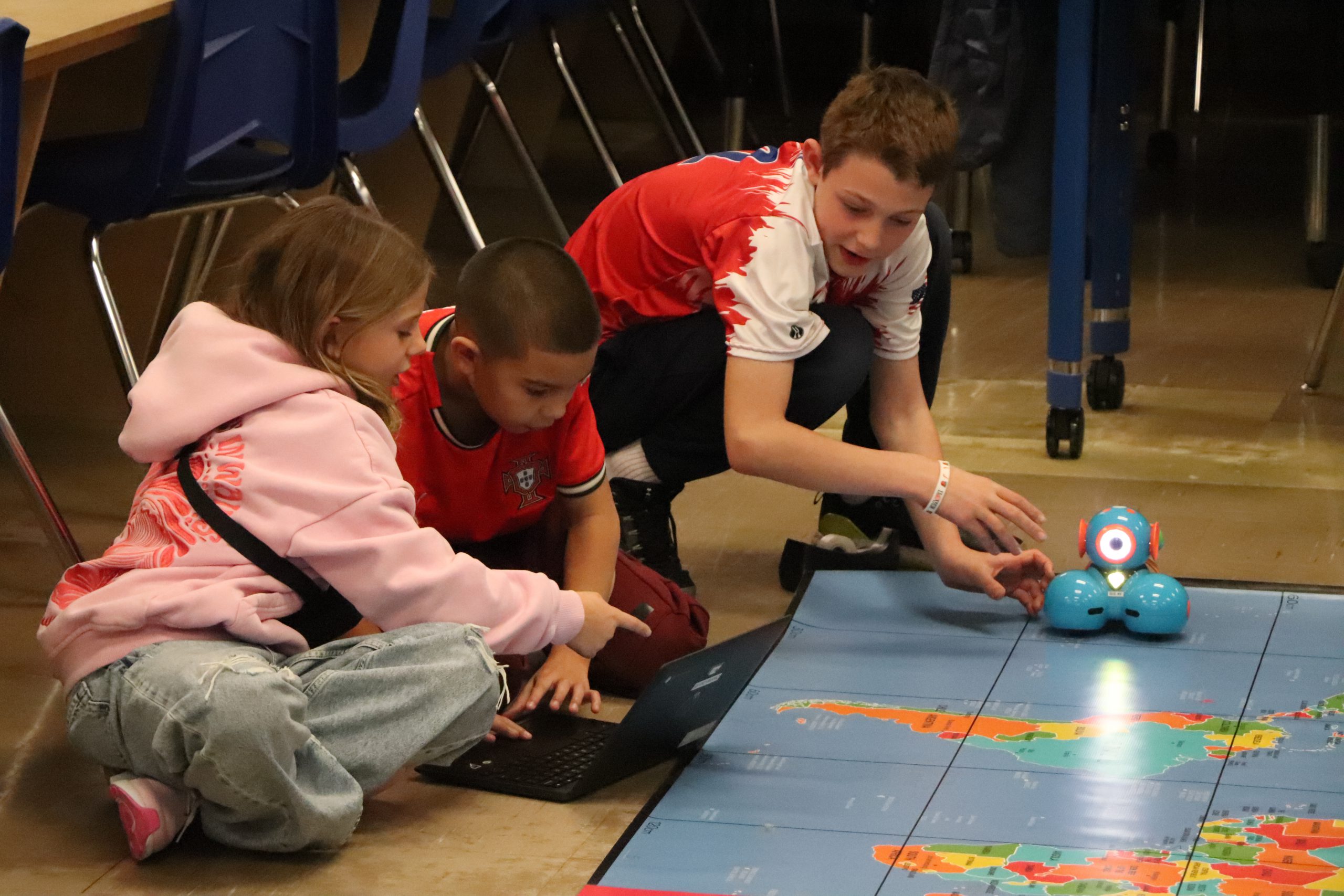 Three students program a robot during the March Madness competition for the robot to shoot a plastic ball. 