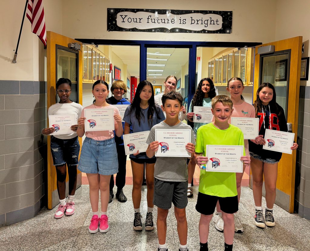 The C. J. Hooker students of the month are standing in the halls with their certificates and smiling for the camera under a sign that reads: Your Future is Bright.