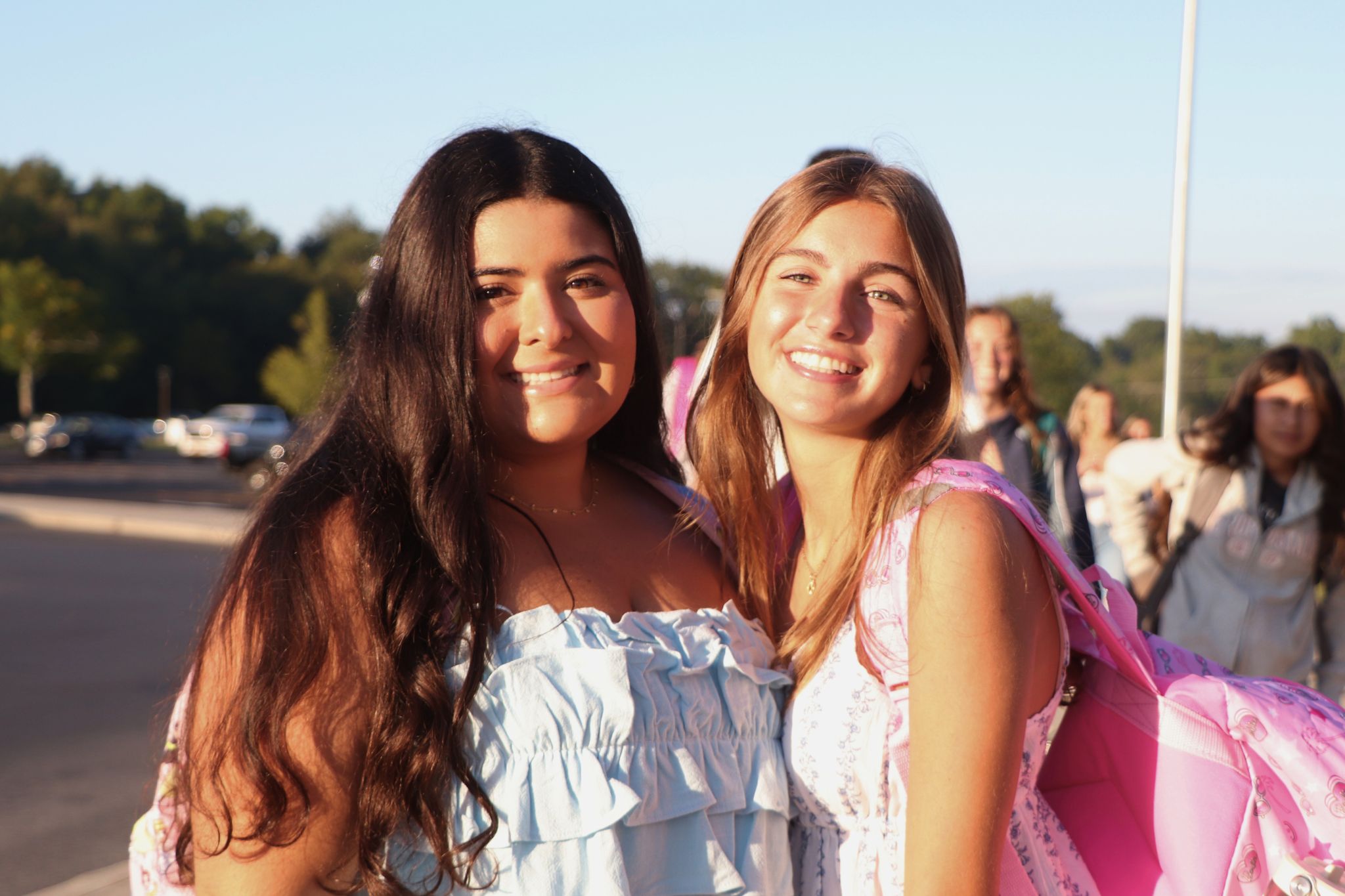 Two students smile for a photo in front of the school on the first day of school. 