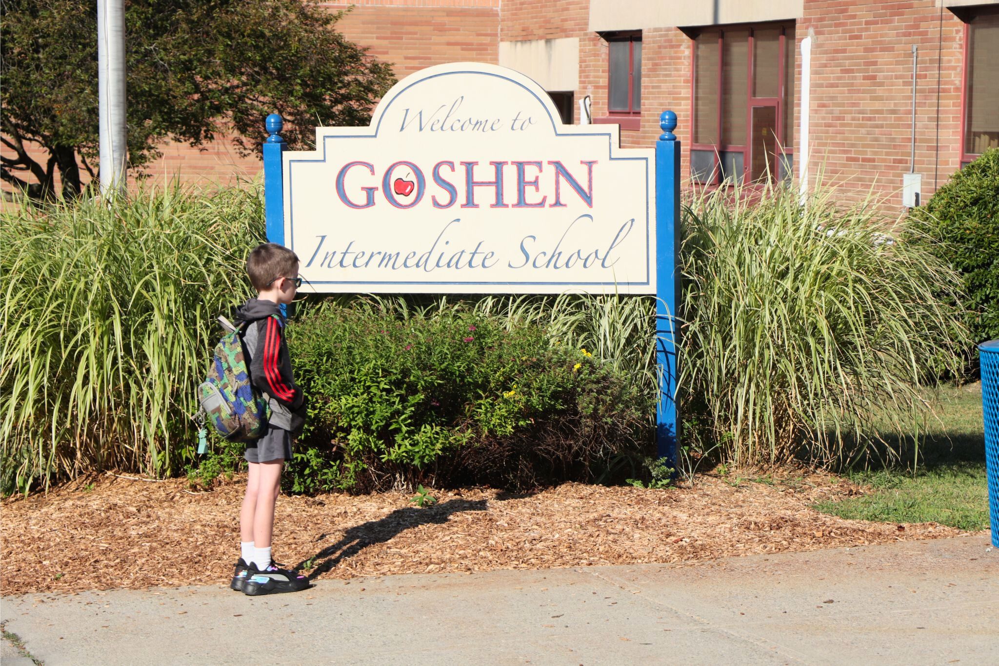 A student stands next to the Goshen Intermediate School sign.