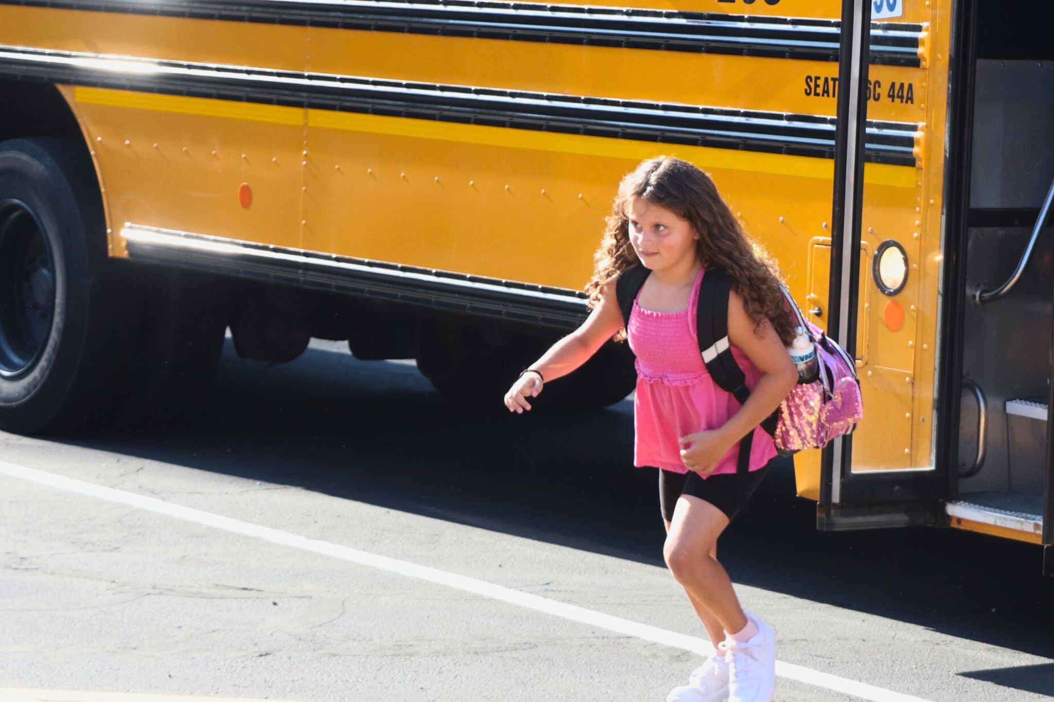 A student gets off the bus and walks into school. 