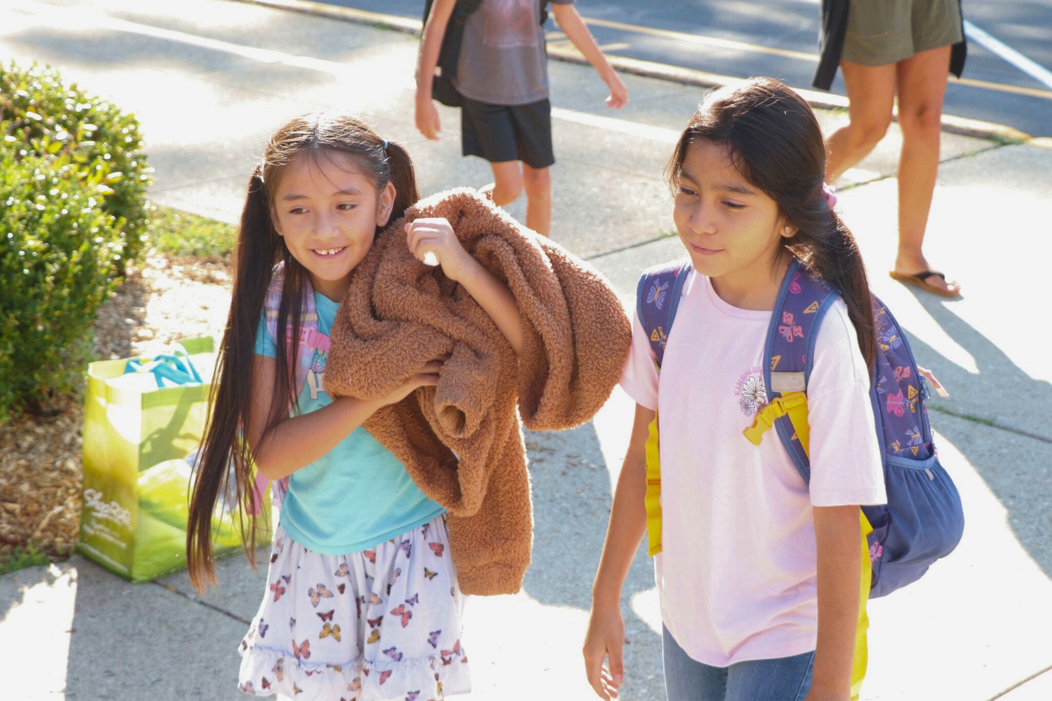Two students walk into school next to each other. 