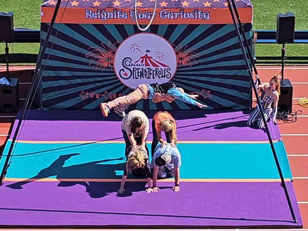 A performer runs and jumps over students at the Circus Splendiferous performance. 