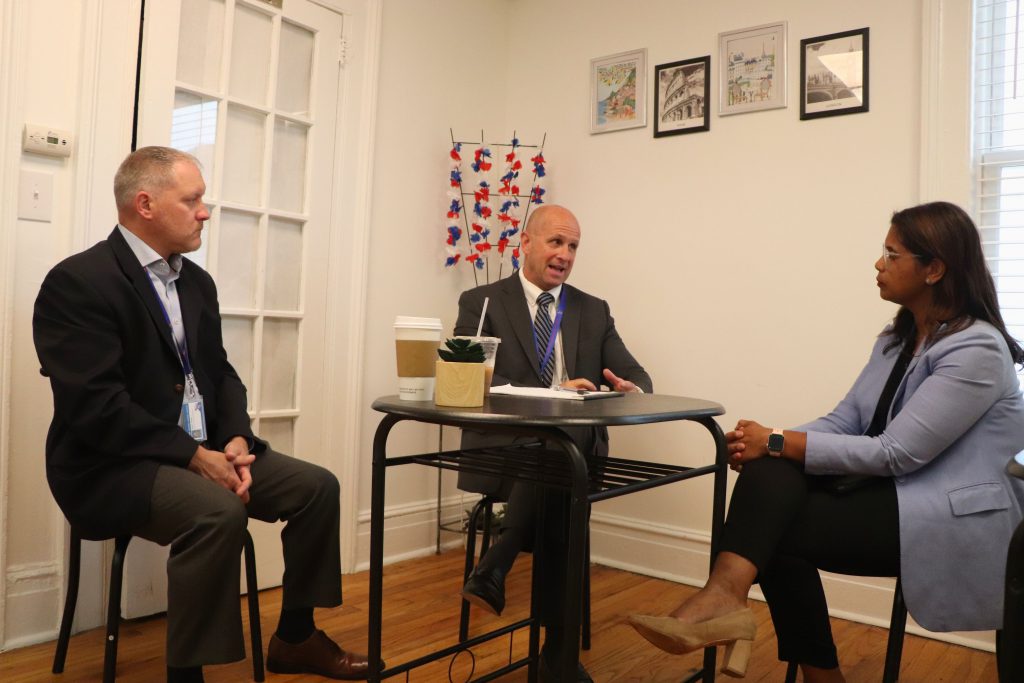 Goshen's superintendent and assistant superintendent speak with a community member sitting at a table.
