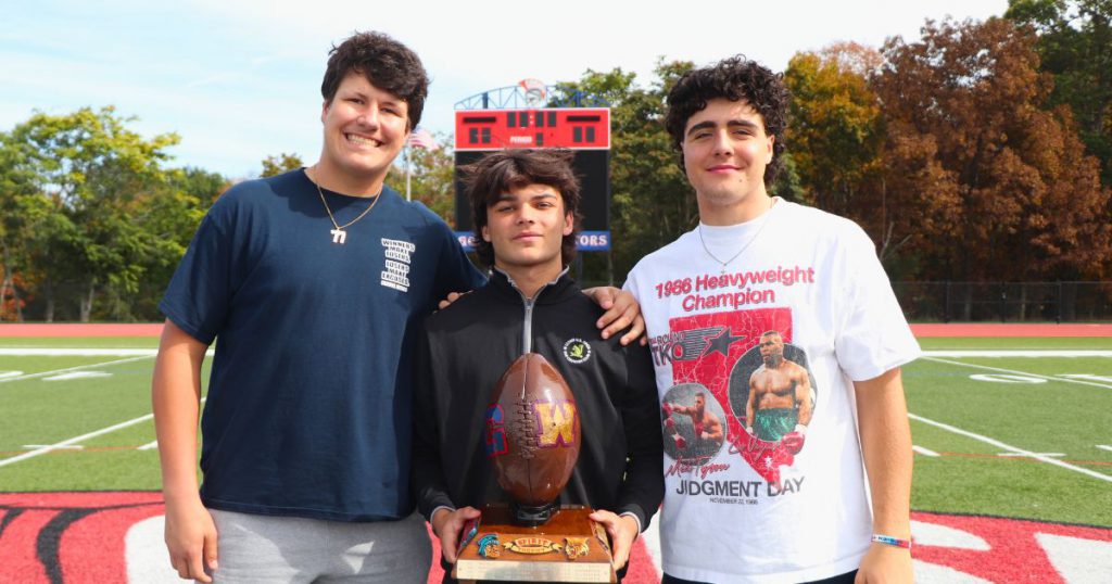 Three Goshen football players pose for a photo on the field. 