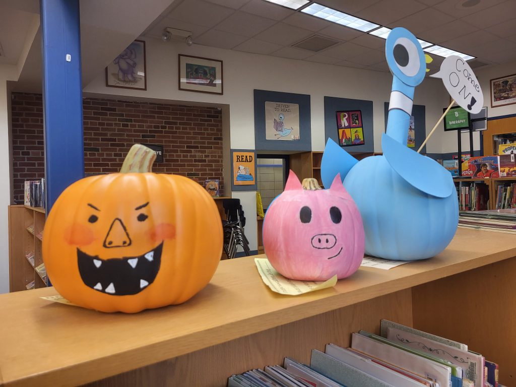 Three pumpkins are decorated like storybook characters on the shelves at Scotchtown Avenue Elementary School's library.