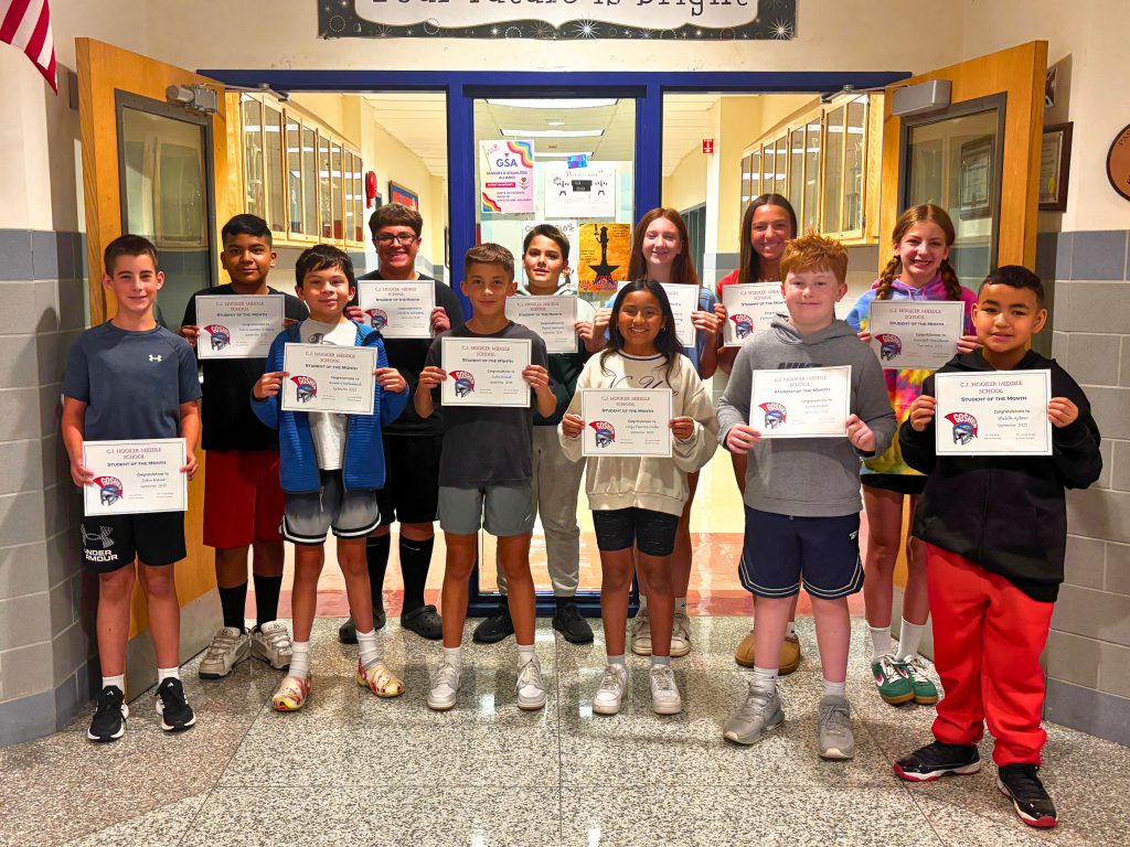 The C. J. Hooker Middle School September students of the month smile for a photo in the hallway and hold up their certificates. 